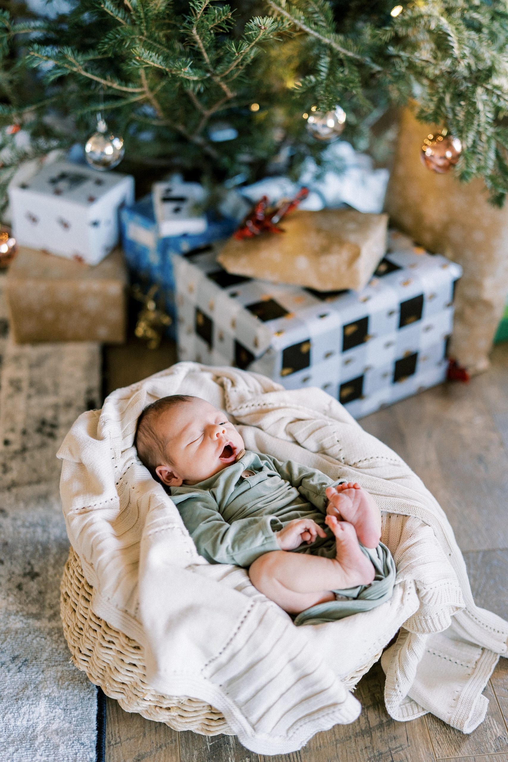 newborn baby boy sleeps in basket by Christmas tree