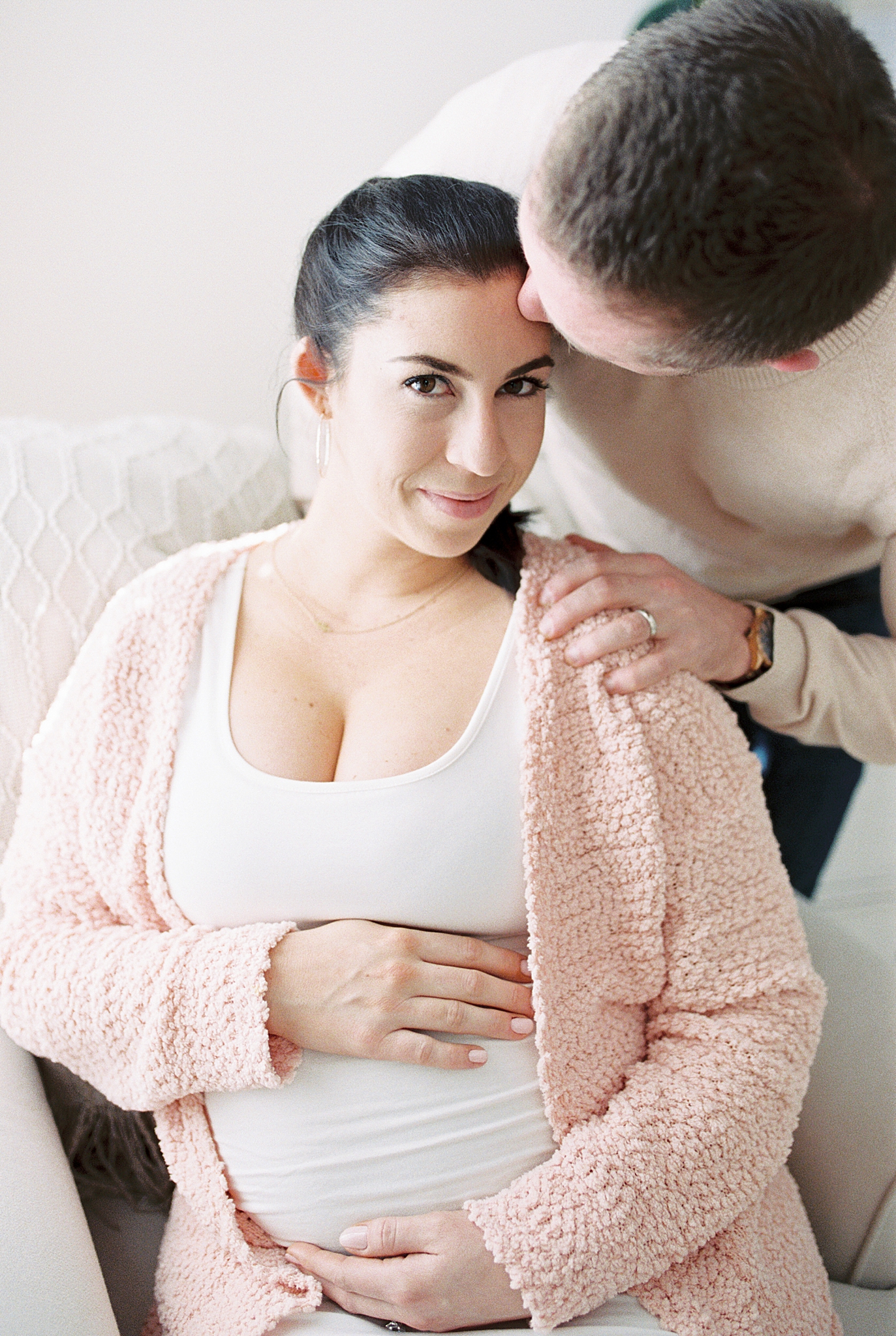 dad kisses mom's forehead during maternity photos at home