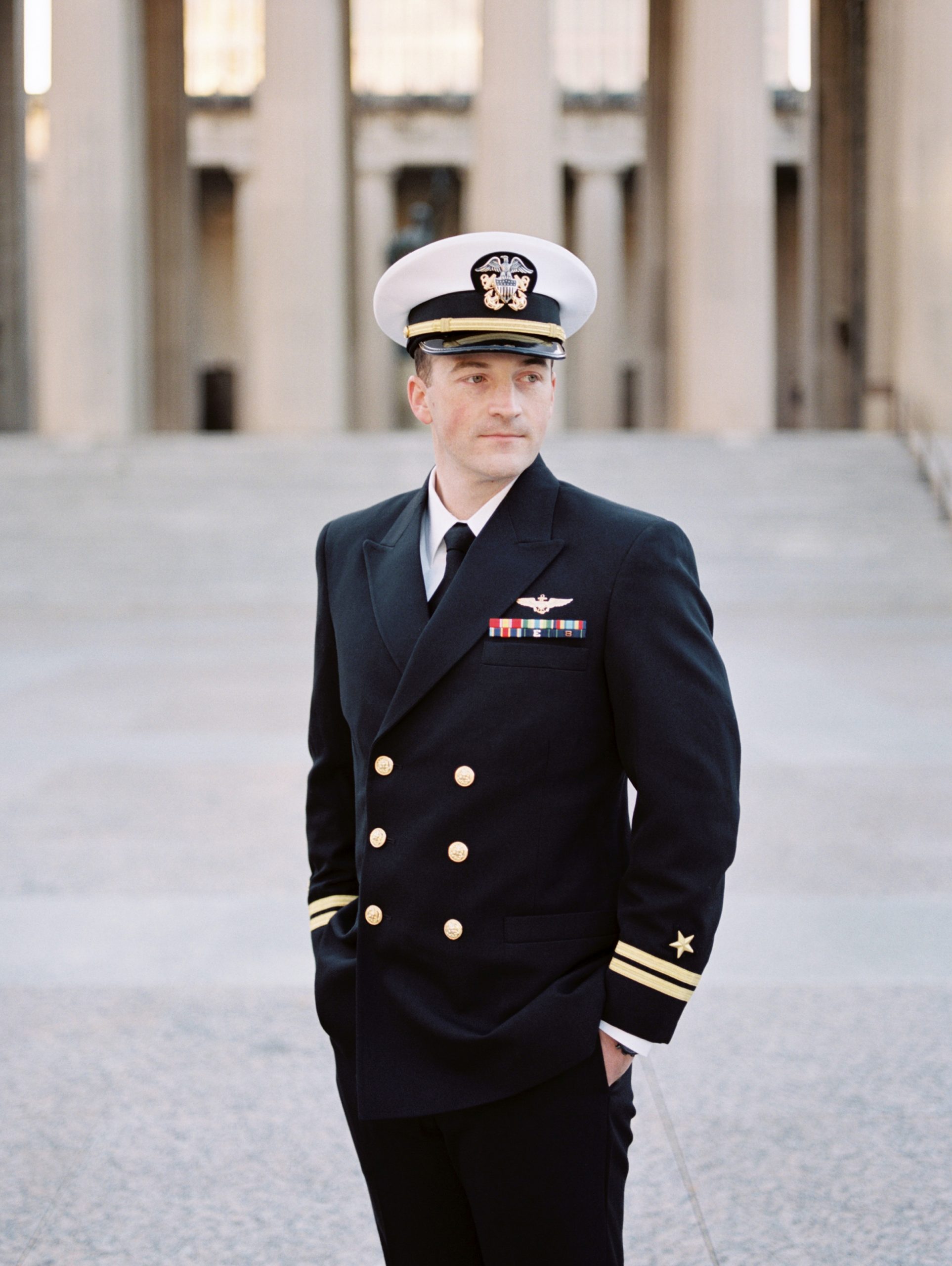 groom in Navy uniform looks over shoulder on wedding day