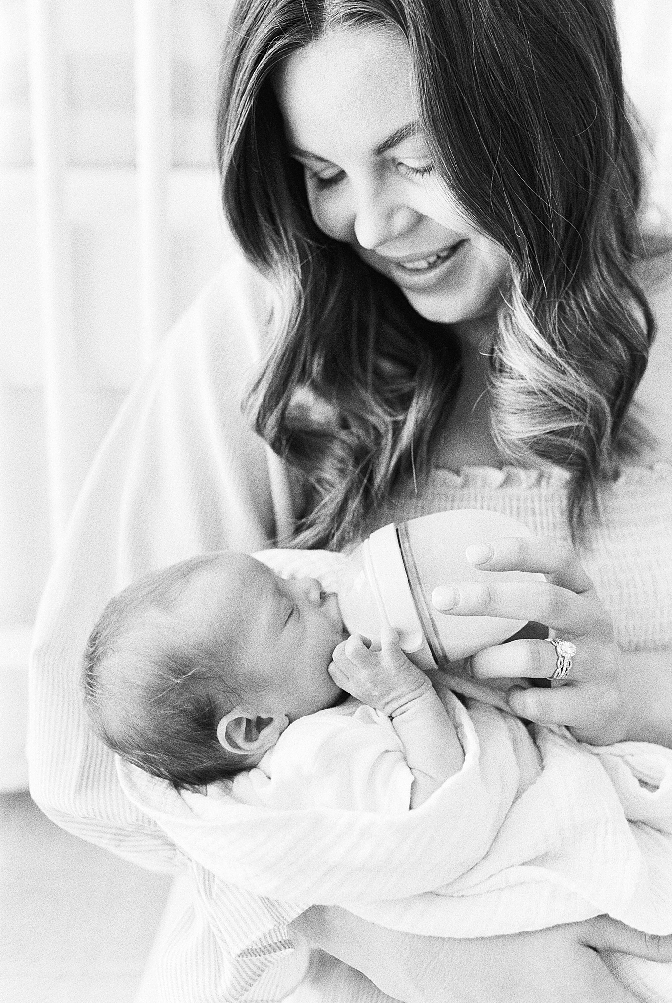mom feeds baby boy during newborn photos at home