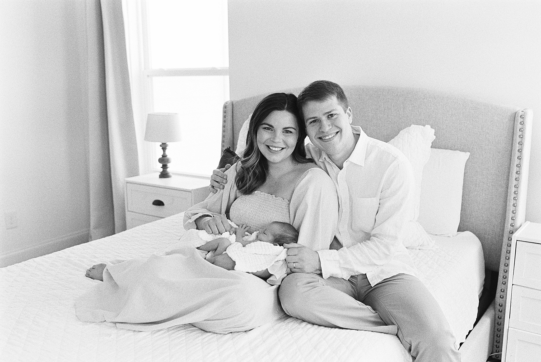 new parents sit on bed during at home newborn portraits