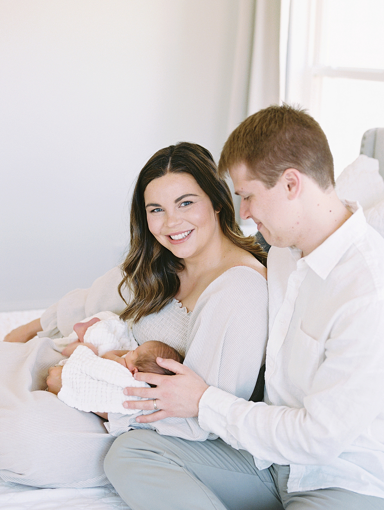 parents sit on bed holding baby boy