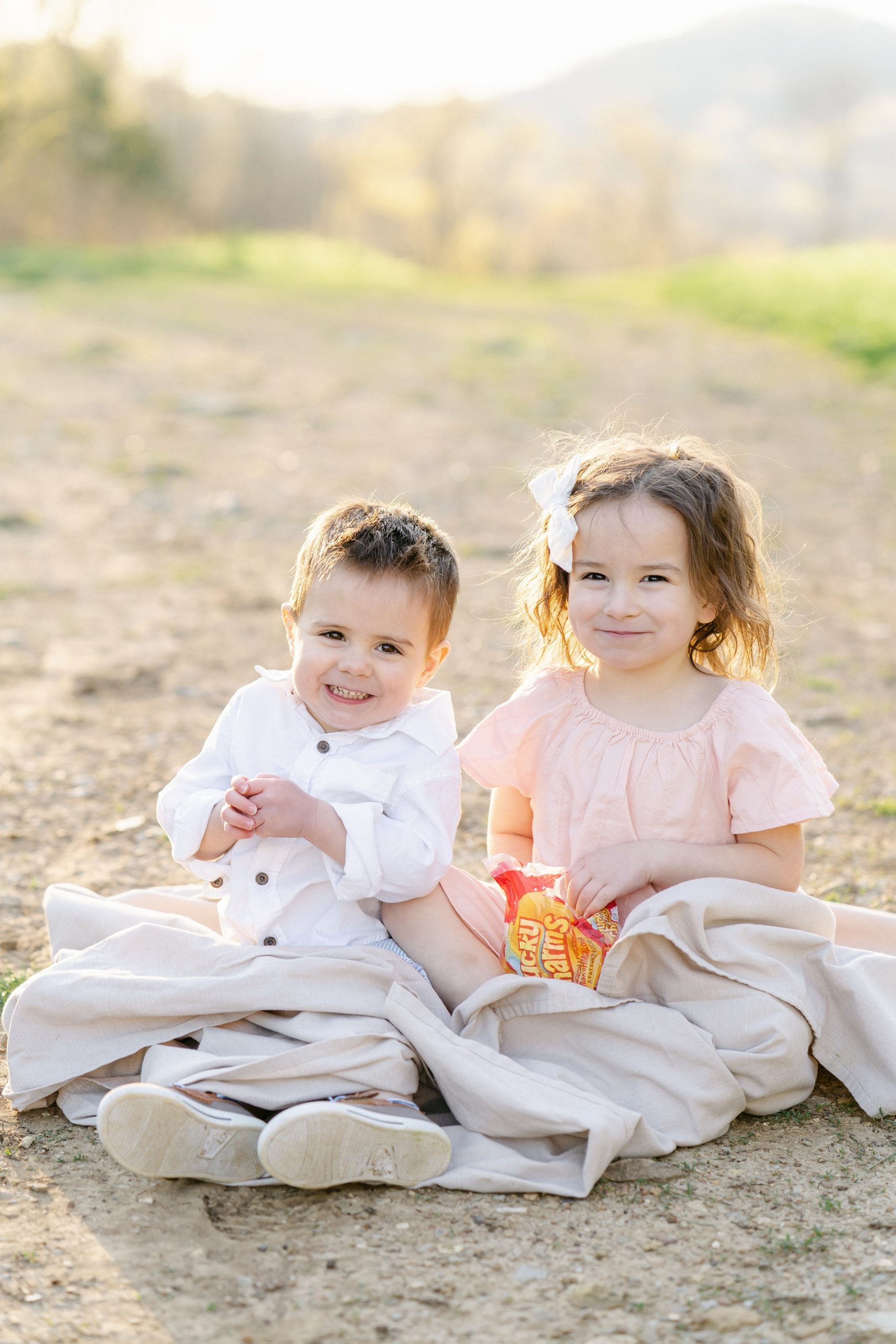 children sit in blanket with treat during family photos