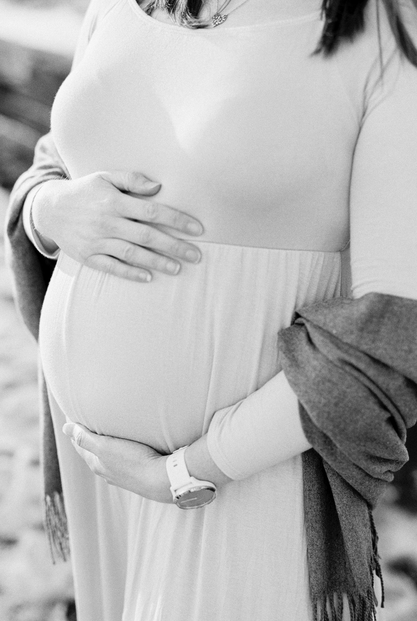 mom holds belly during Ellington Agricultural Center maternity portraits