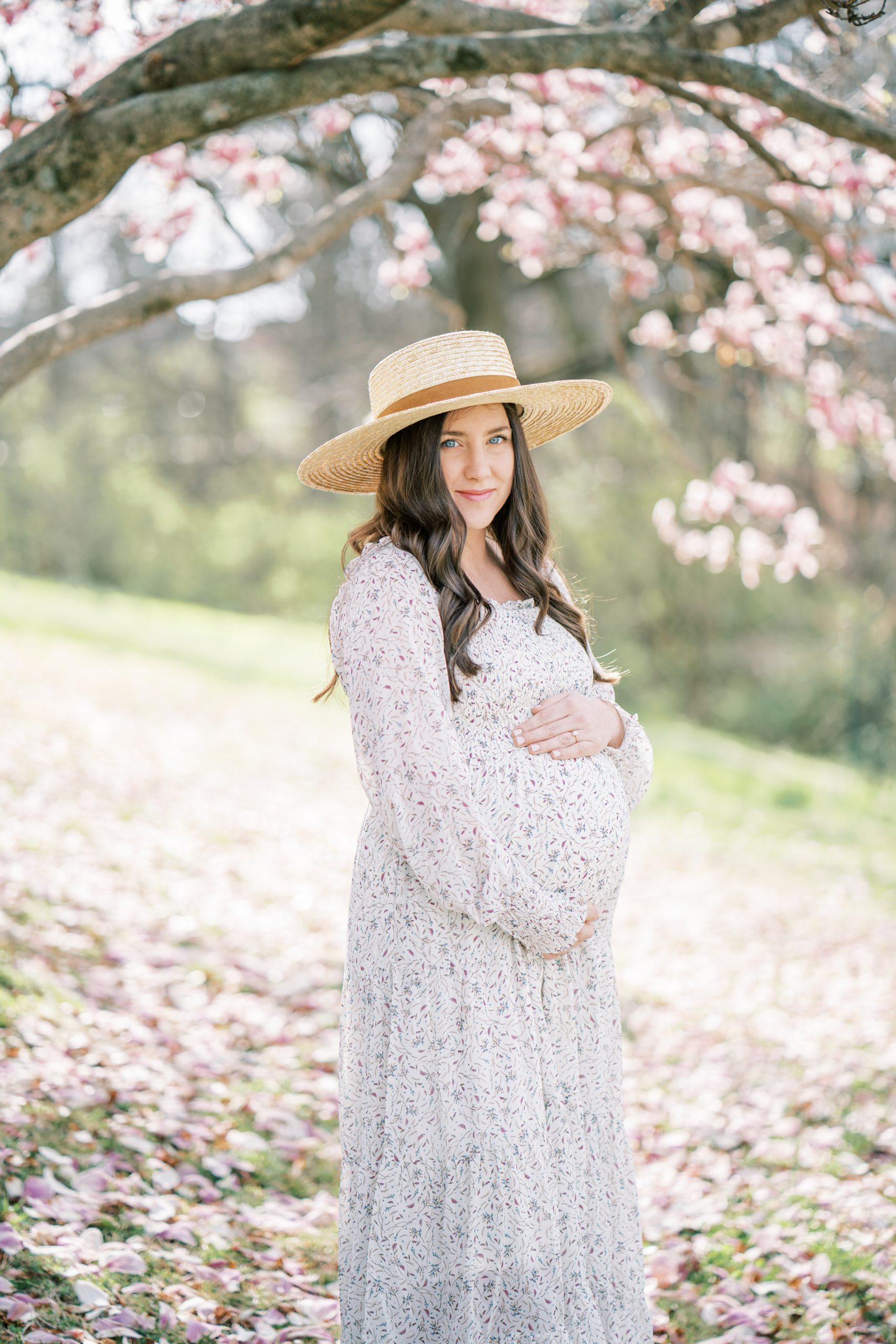 mom holds baby belly under cherry blossom tree