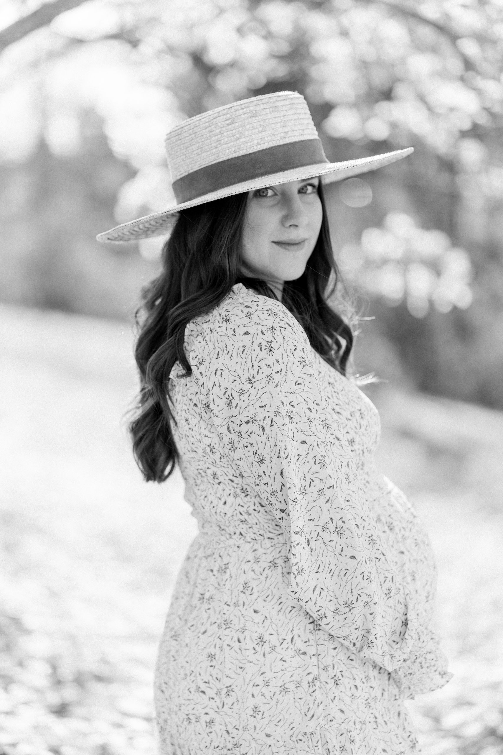 mom in wide brim hat looks over shoulder during maternity
