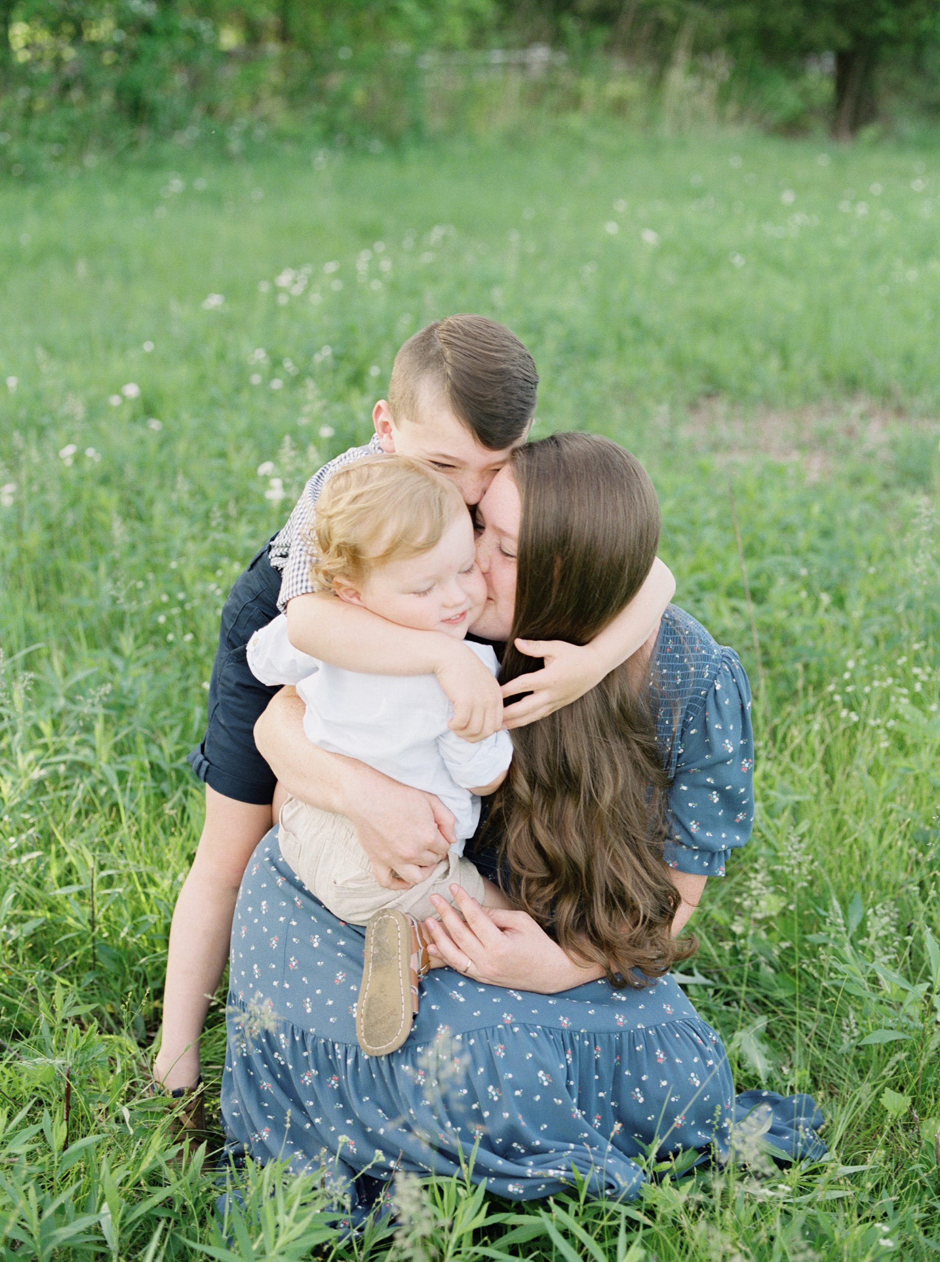 sons hug their mama in grass during family portraits