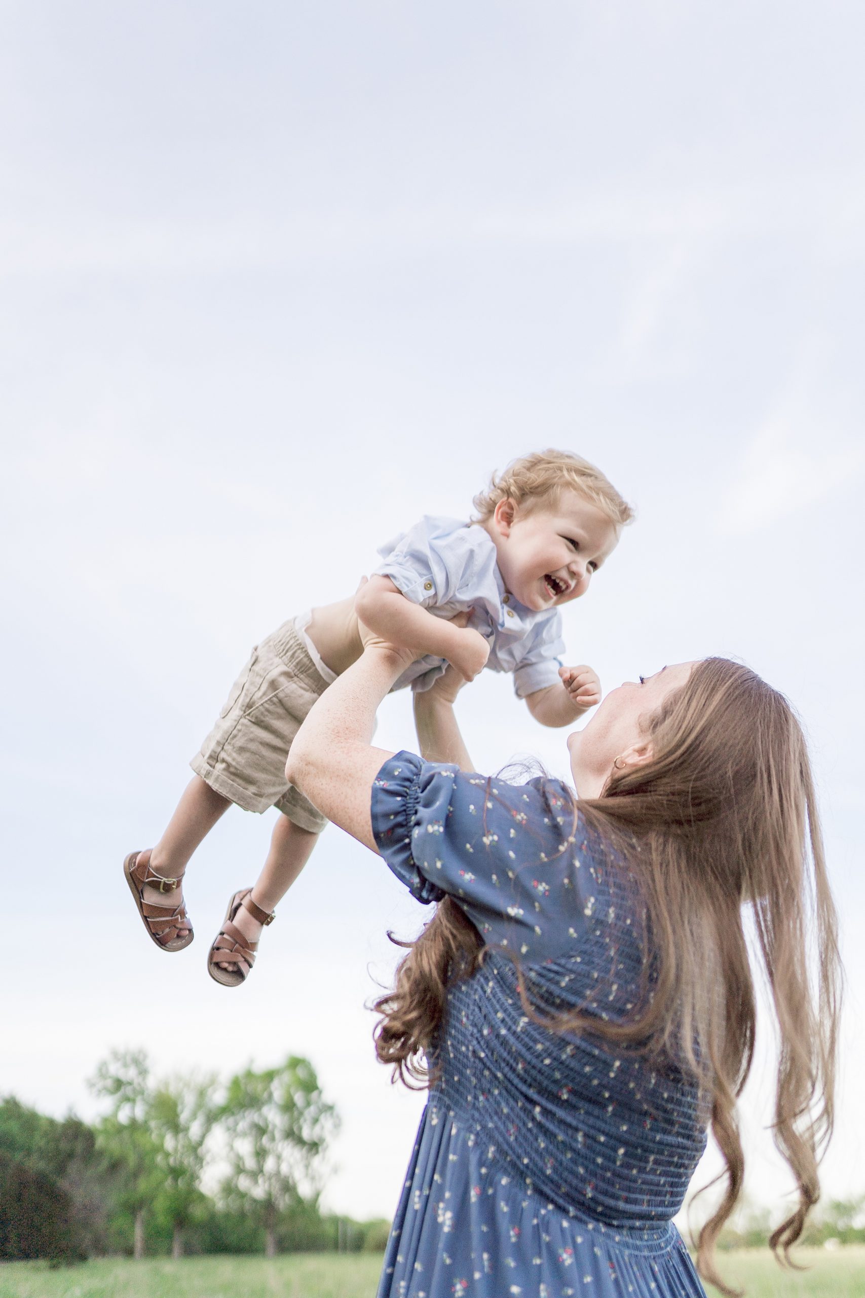 mom holds youngest son in air as he giggles during Family Session in Murfreesboro