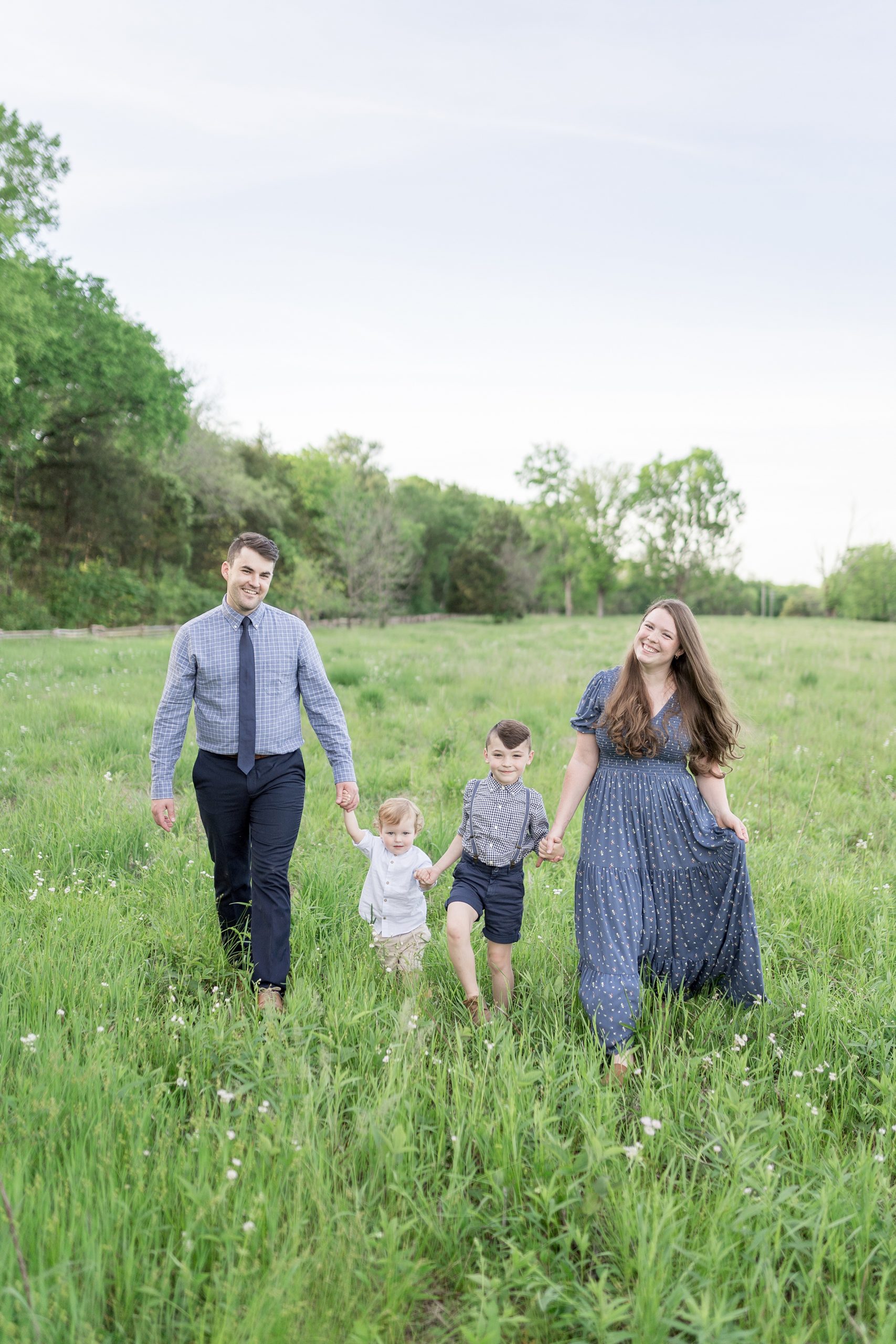 family holds hands and walks together in a field