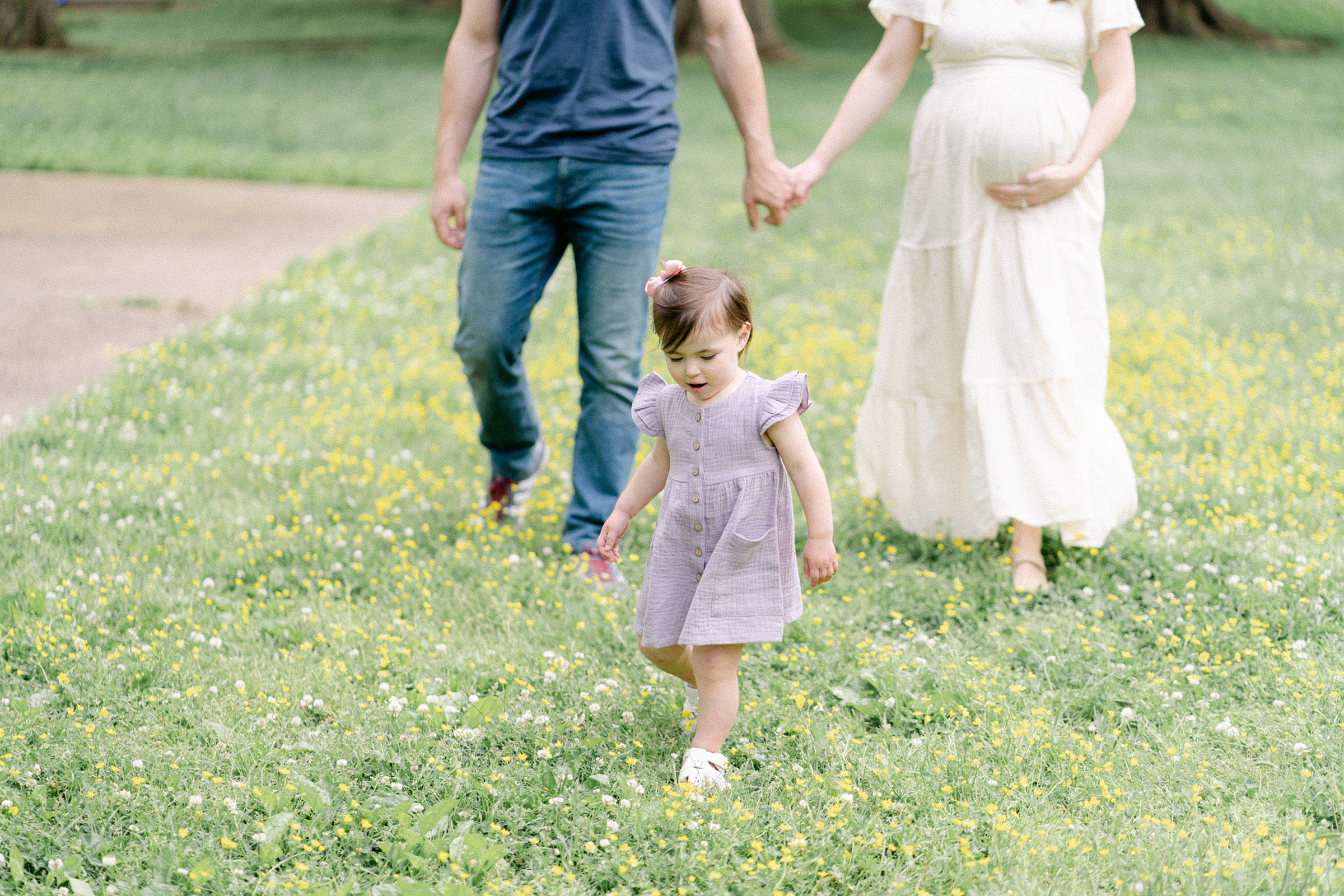 daughter walks ahead of mom and dad holding hands