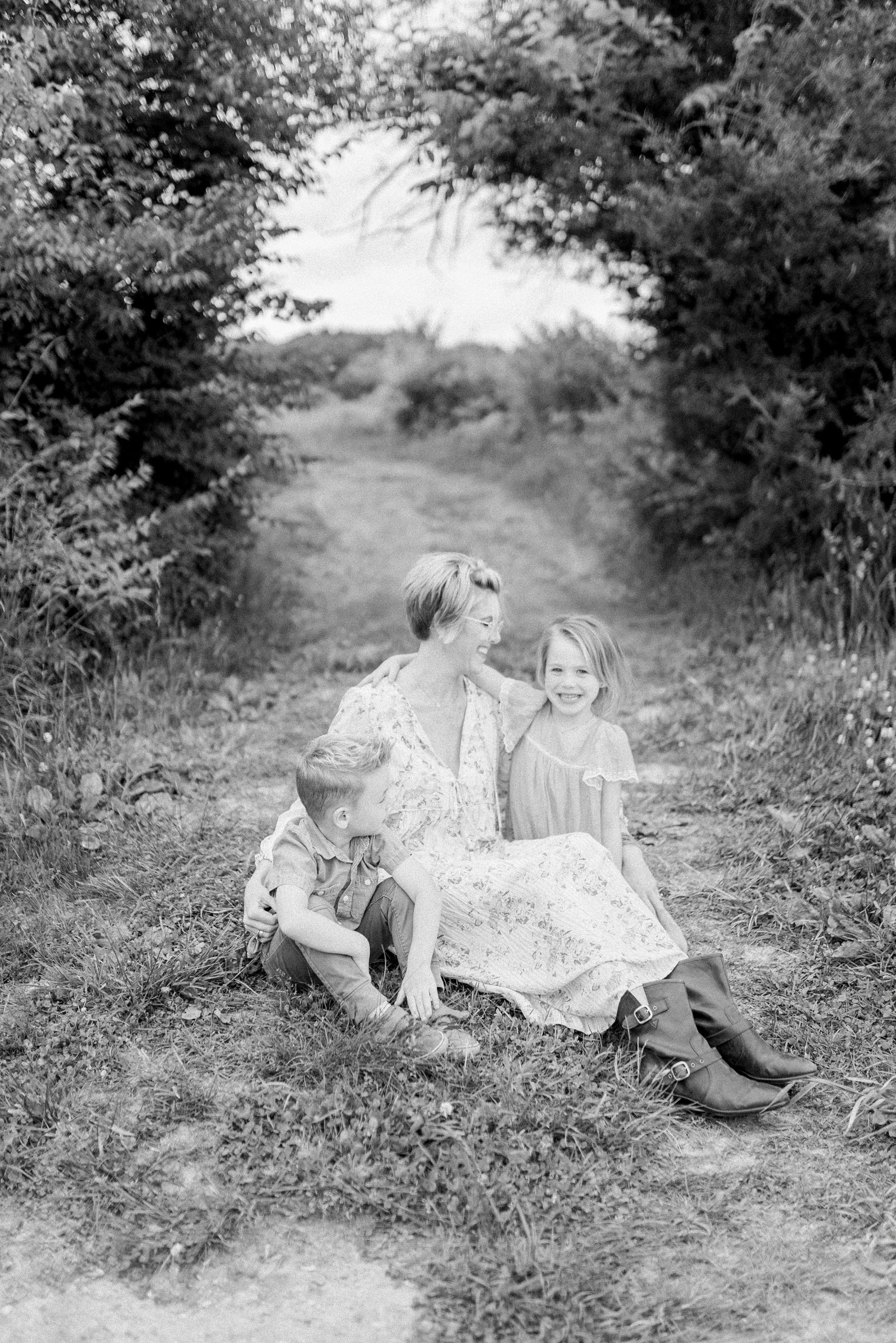 black + White photo of mom sitting in grass with two kids