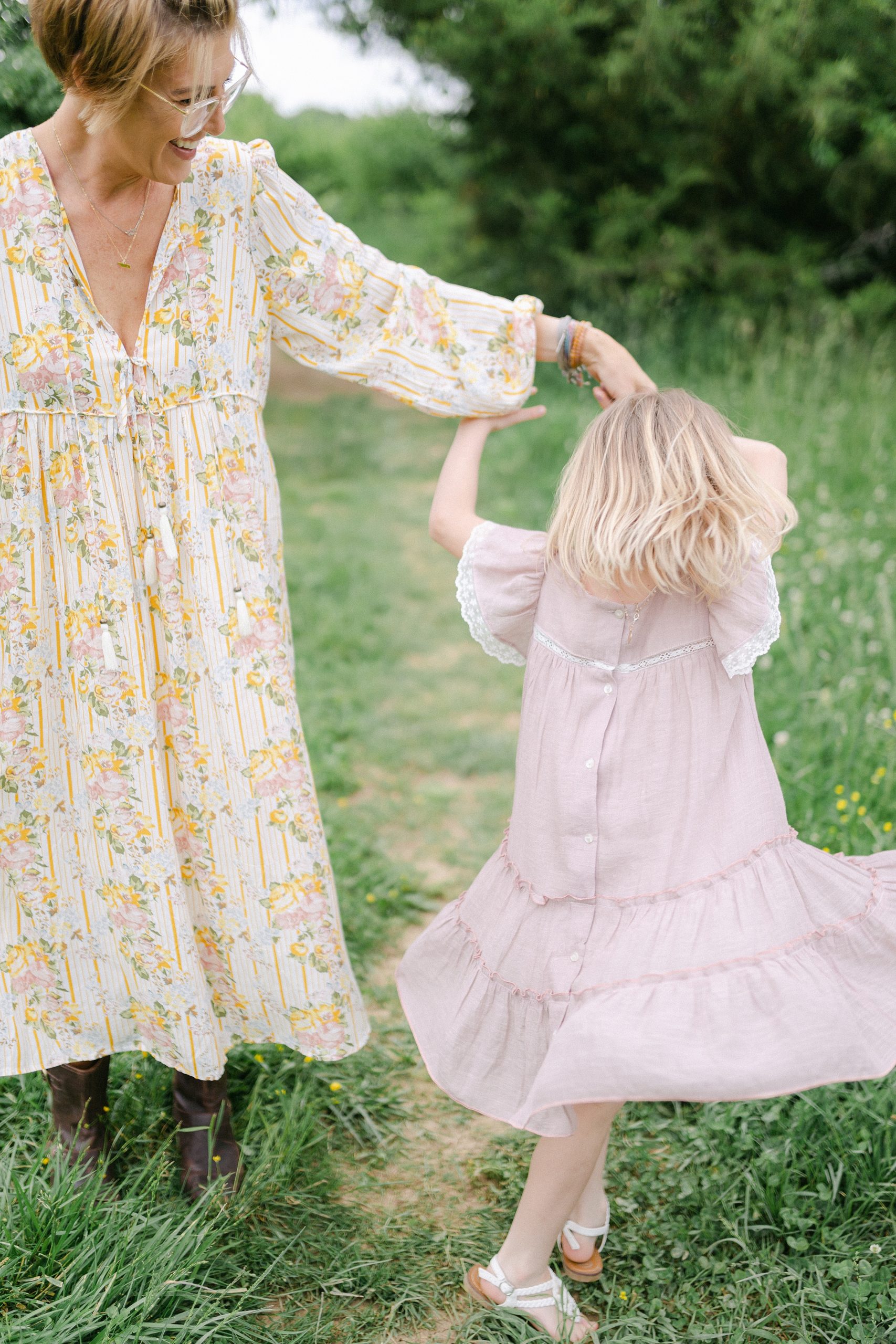 mom twirls little girl around showing off her pink dress