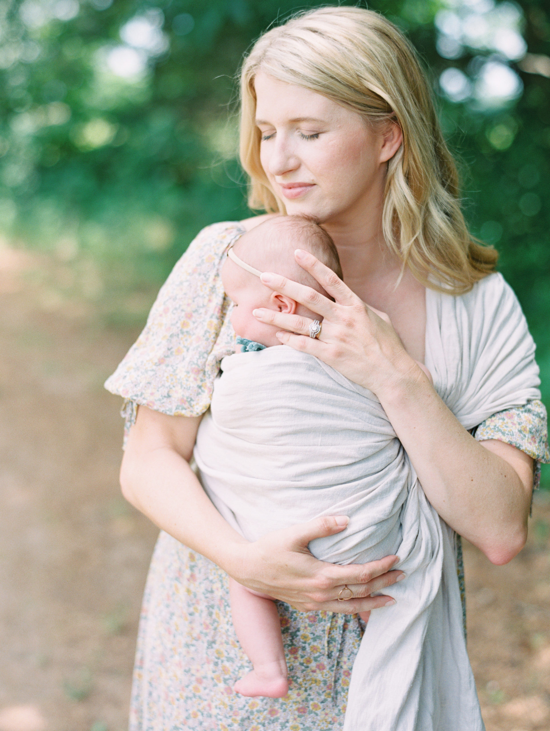 Mother holds baby close during portrait session outside