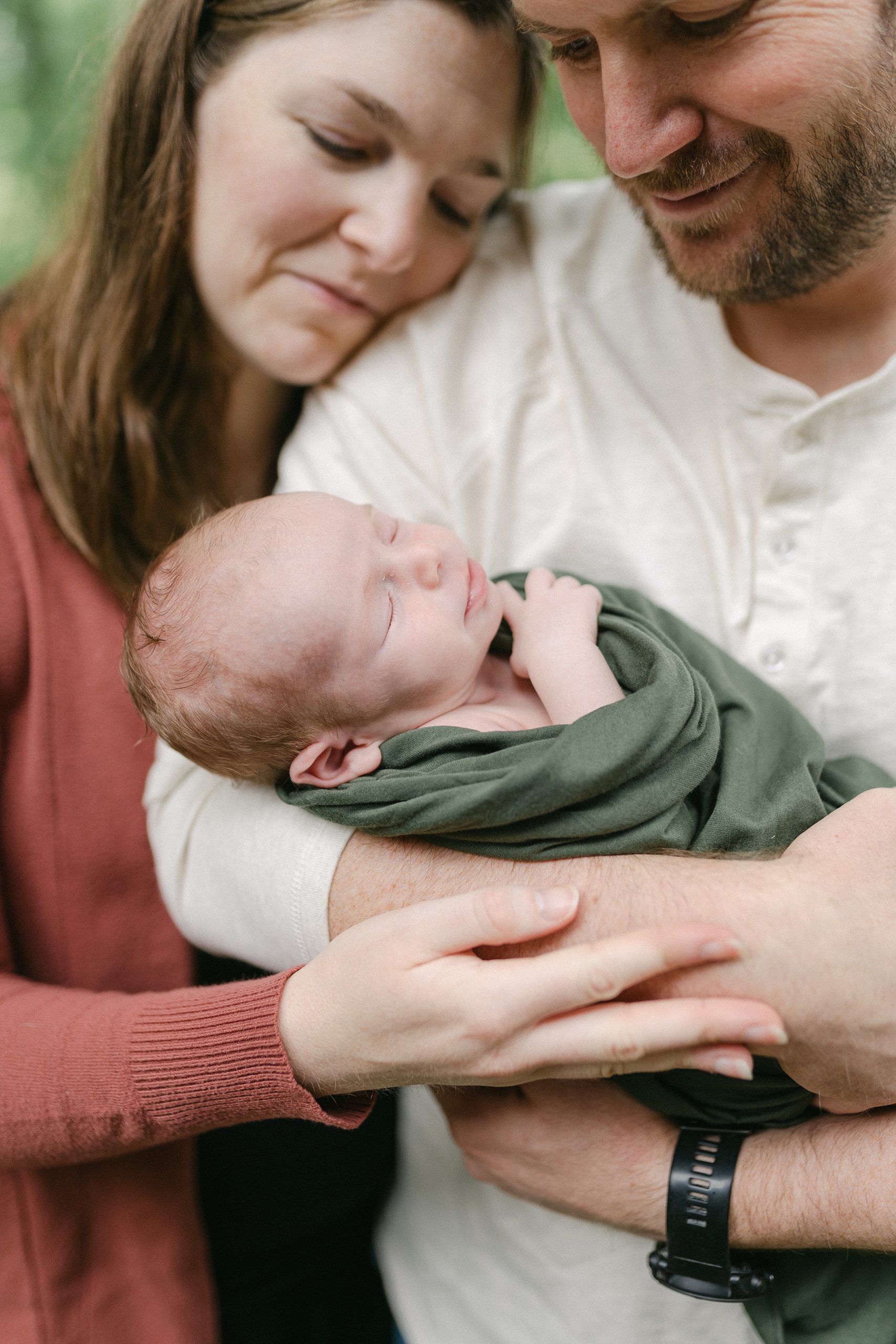 newborn boy wrapped in green blanket during newborn portraits