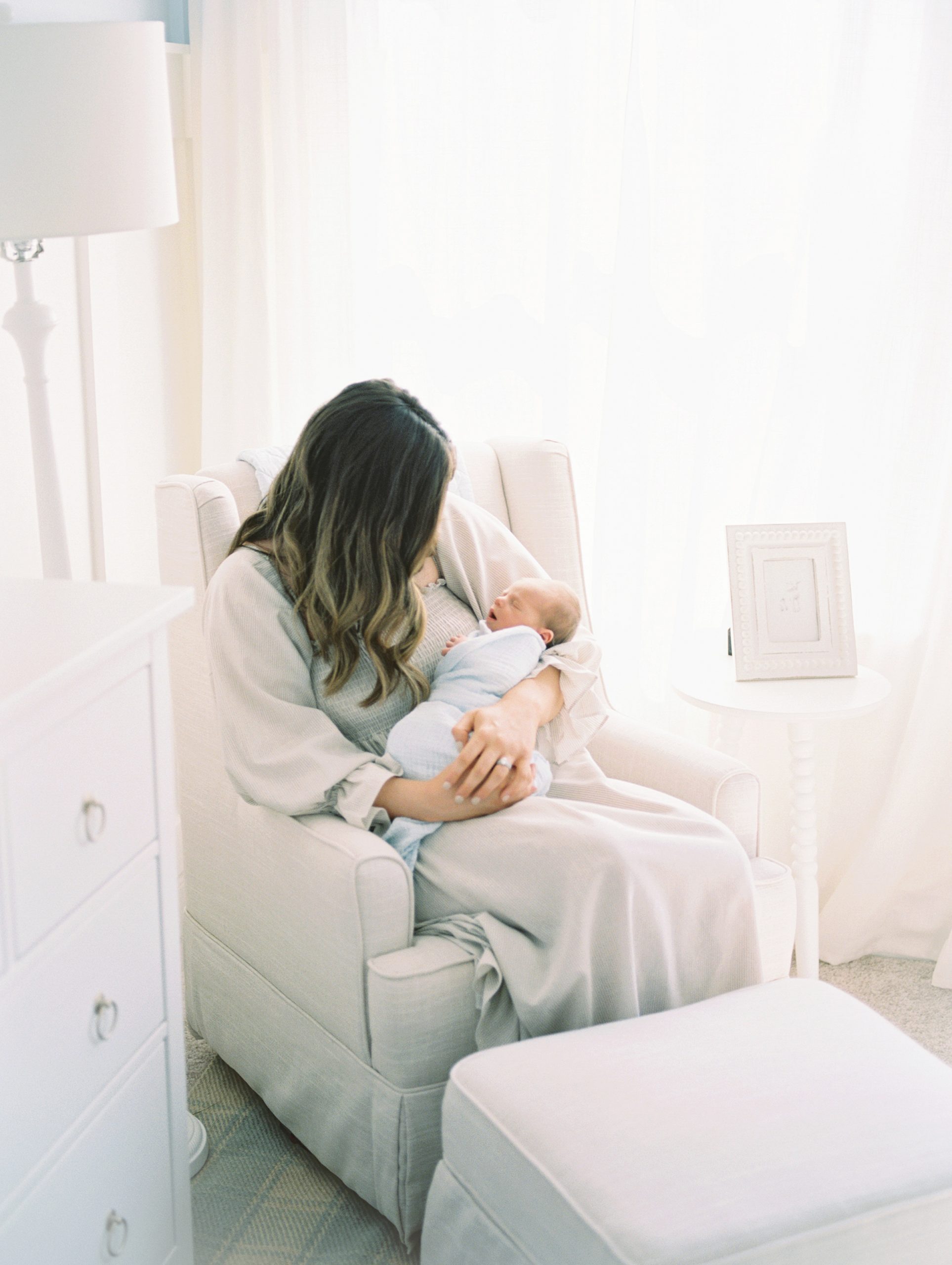 Murfreesboro Mom holds newborn in side lighting of nursery during in-home newborn session