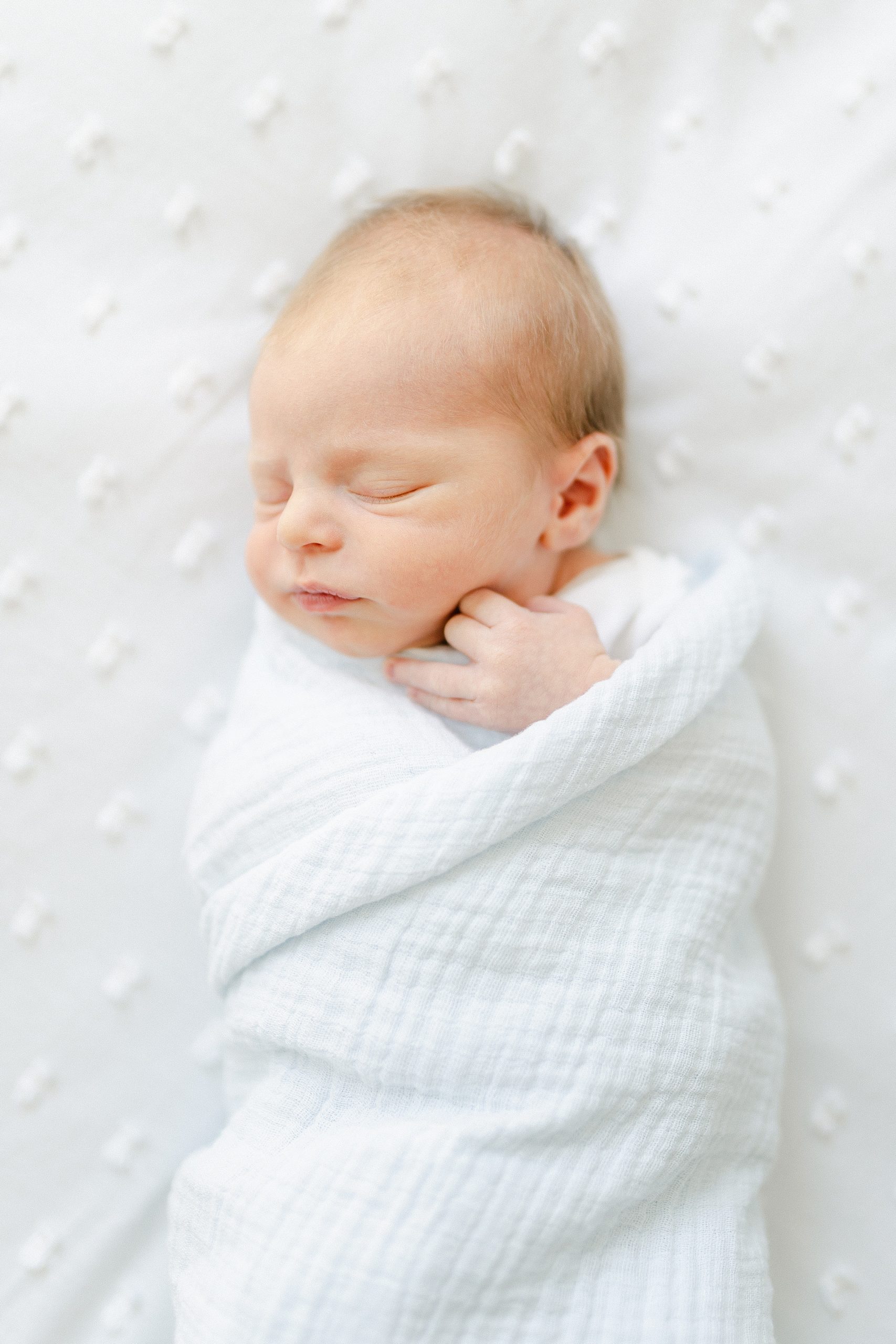 swaddled newborn baby boy during in-home newborn session
