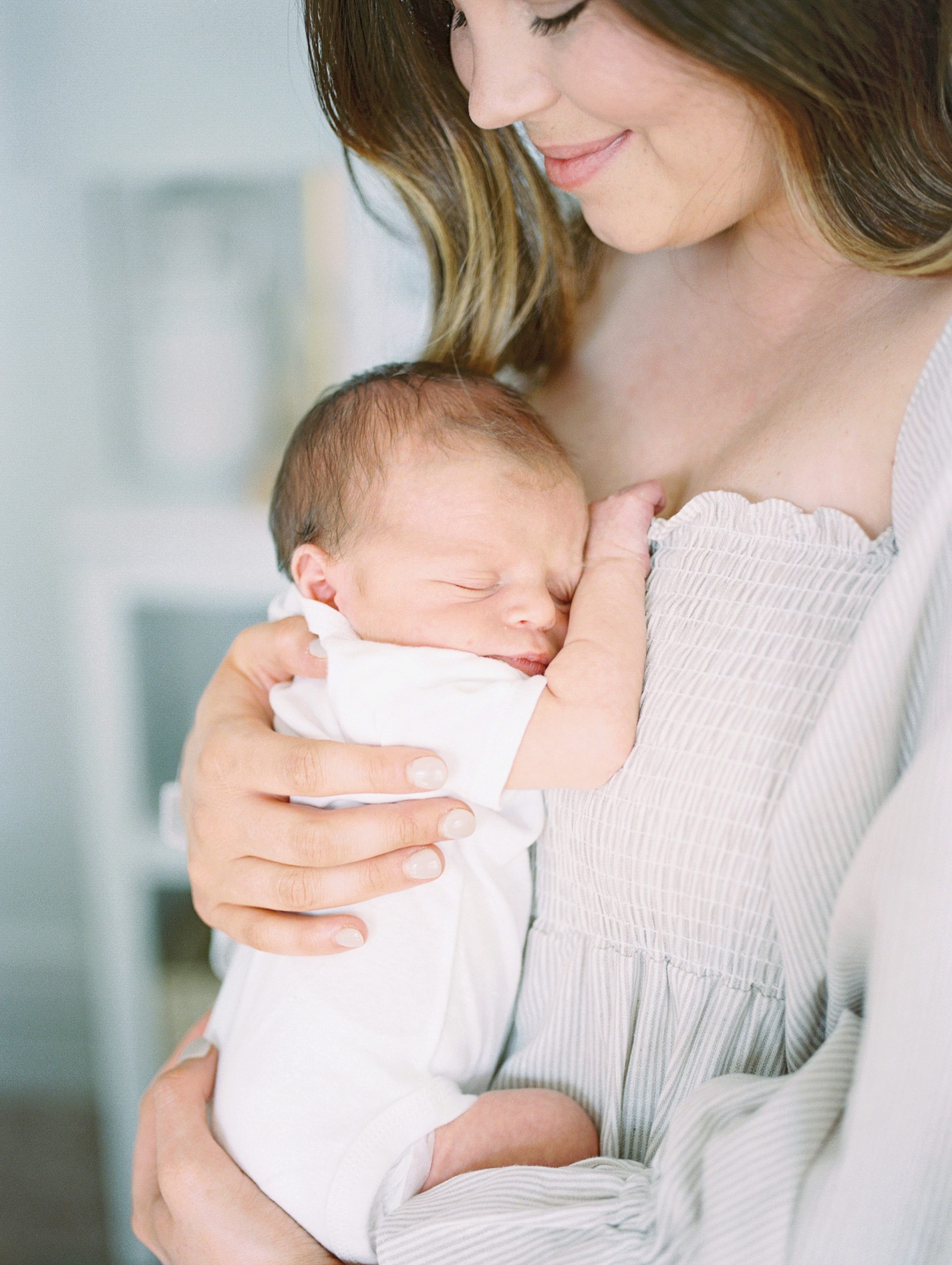 mom holds newborn baby boy on chest during in-home newborn session