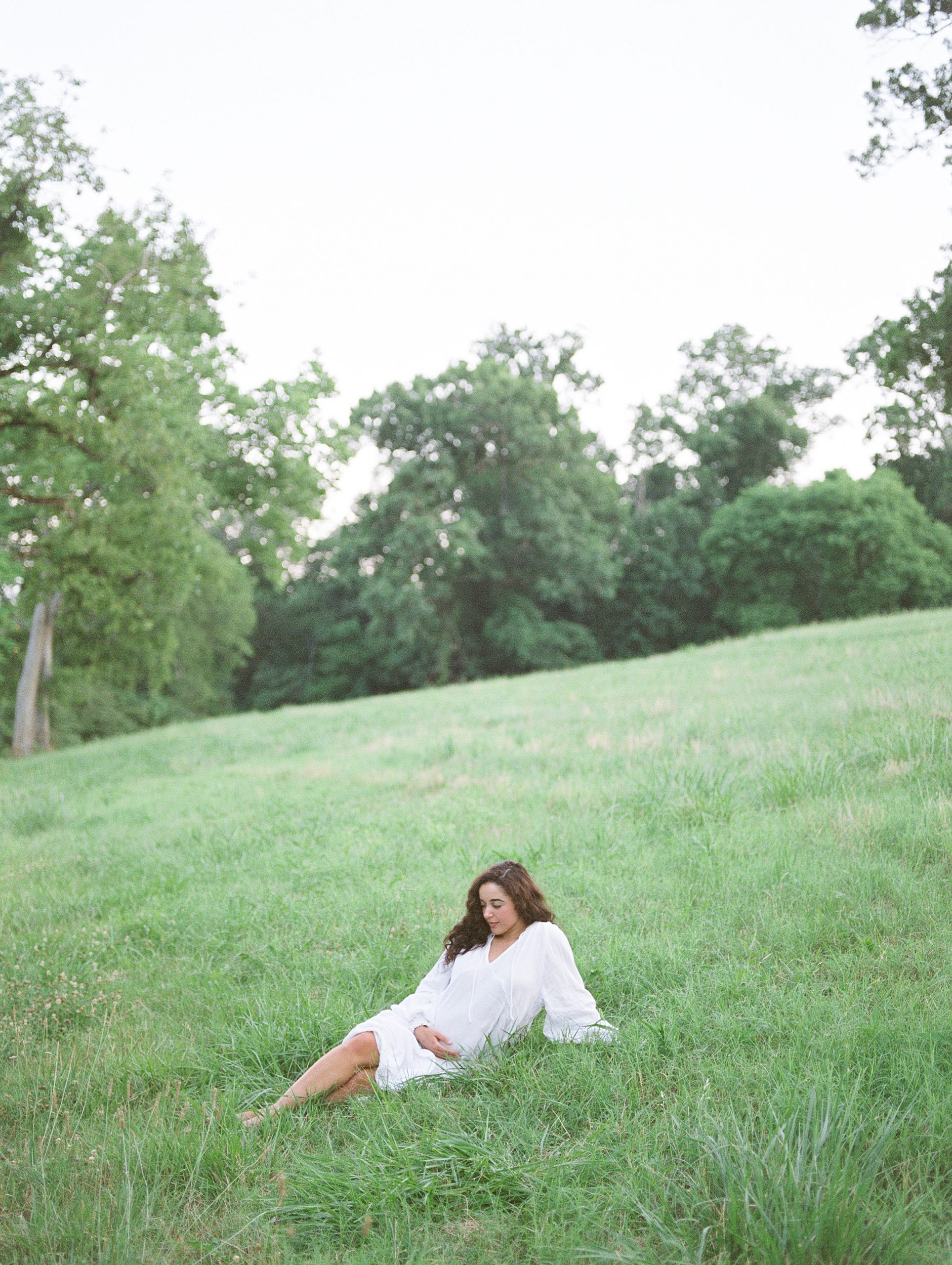 Woman lays on grassy hillside for Maternity Session in Nashville TN