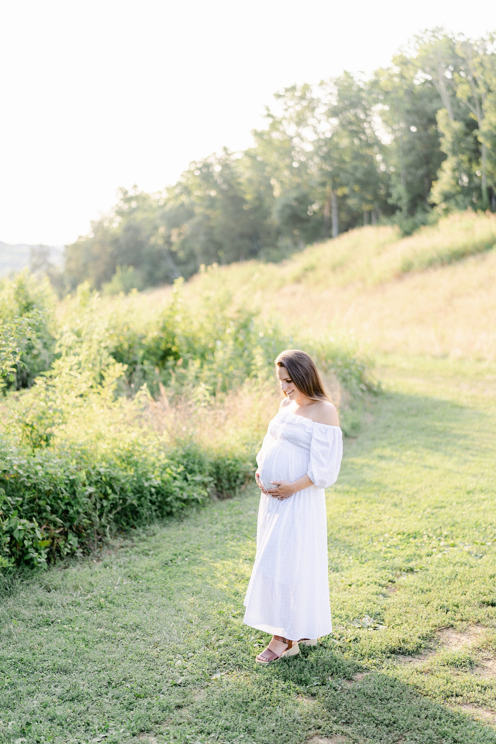 mom to be walks along grass path during TN maternity session
