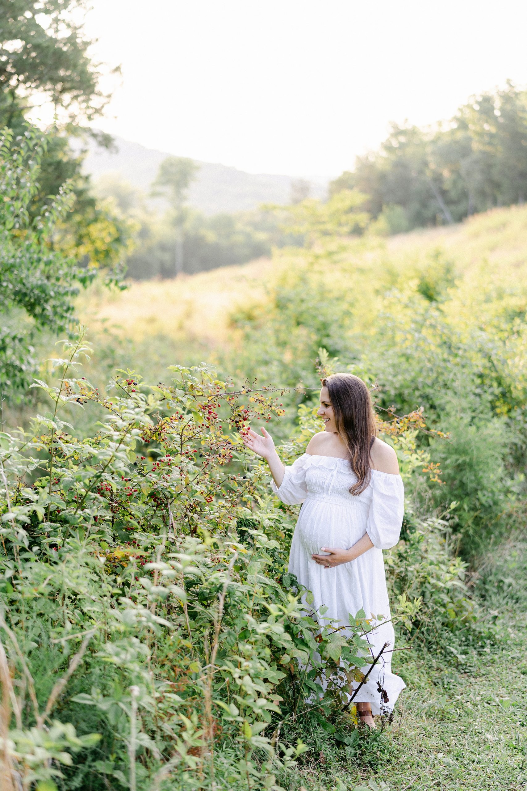 mom to be stands among the tall flowers on a grassy hillside in Brentwood TN Maternity Session by Grace Paul Photography