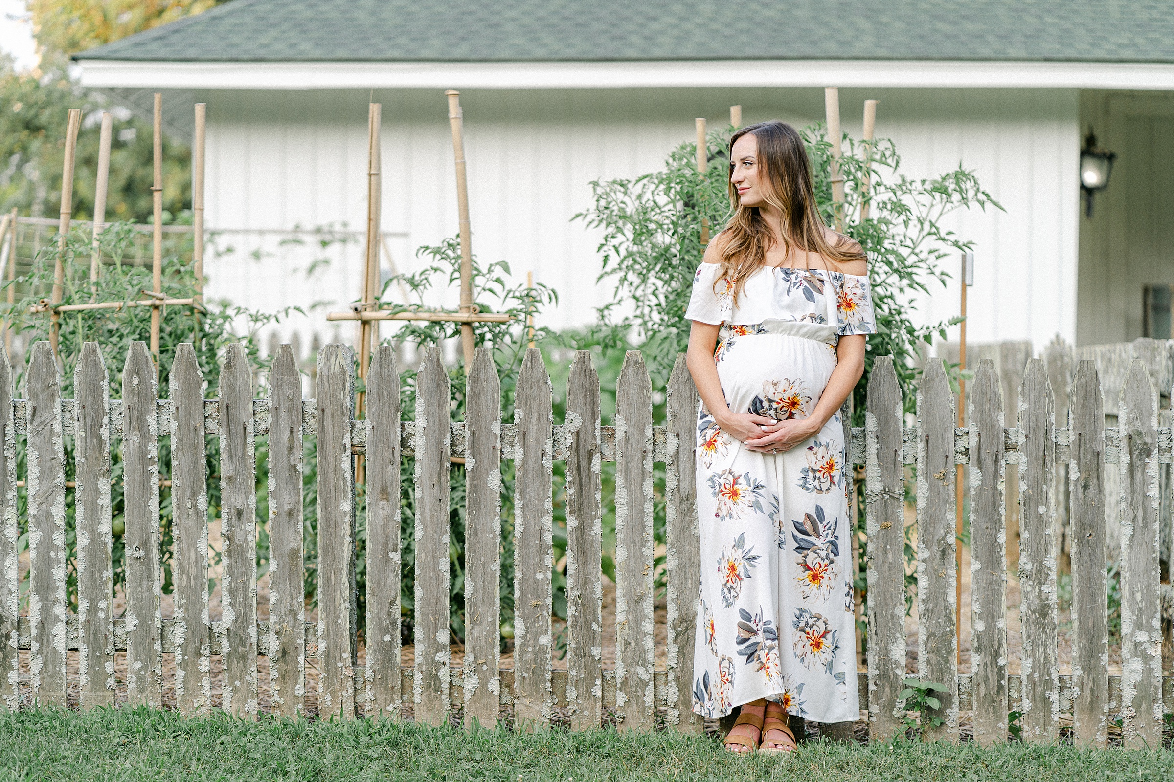 Mom stands near old wooden fence at Ellington Agricultural Center during maternity photo session