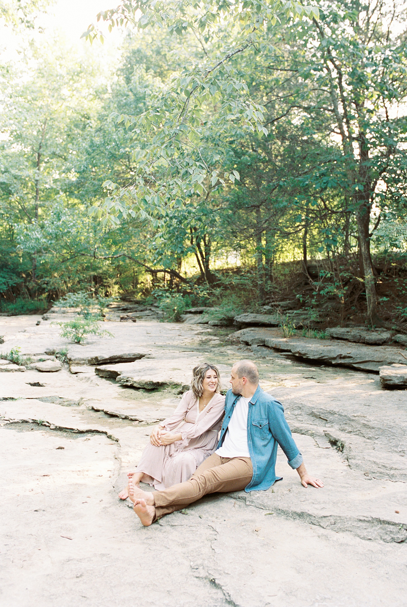 couple sits on rocks near stream in Nashville TN at Ellington Agricultural Center